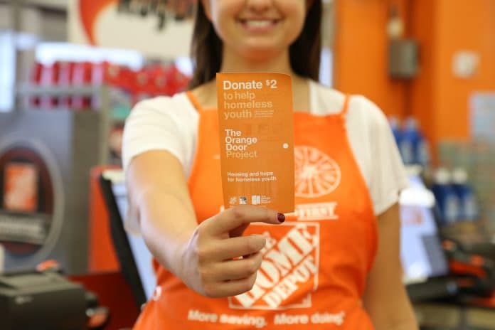 A Home Depot employee holding an Orange Door (being sold to support homeless youth).